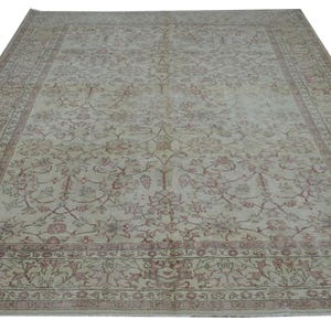 May include: Large, rectangular area rug with an intricate floral pattern in shades of beige, red, and green. The rug has a detailed border and a distressed, vintage appearance, suitable for living rooms or bedrooms.