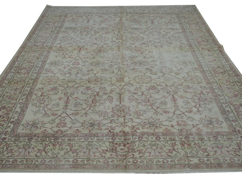 May include: Large, rectangular area rug with an intricate floral pattern in shades of beige, red, and green. The rug has a detailed border and a distressed, vintage appearance, suitable for living rooms or bedrooms.