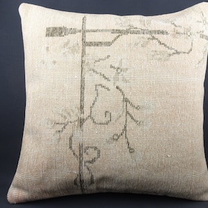 May include: A beige throw pillow with a black and white floral design. The pillow is made of a soft, woven fabric.