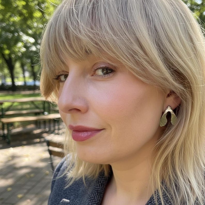 May include: A silver-toned earring shaped like a maple seed pod, also known as a samara, featuring a smooth, metallic finish. The earring is worn on the earlobe and has a distinct bifurcated design that mimics the natural form of a winged seed.