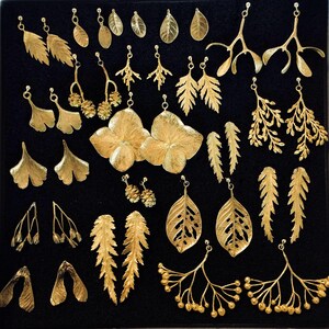 Puede incluir: Una colecci&oacute;n de pendientes dorados con diversos dise&ntilde;os bot&aacute;nicos, incluyendo hojas, ramas y formas de flores. Los pendientes se exhiben sobre una superficie negra, mostrando sus intrincados detalles y variados estilos. La colecci&oacute;n incluye varios pares de pendientes.