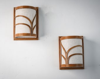 May include: Two brown wicker wall sconces with white fabric shades. The shades have a woven pattern.
