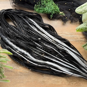 Puede incluir: Dreadlocks en blanco y negro con detalles plateados. Los dreadlocks están dispuestos sobre una superficie de madera. La imagen también incluye un logotipo que dice "Dread5 FOREST".