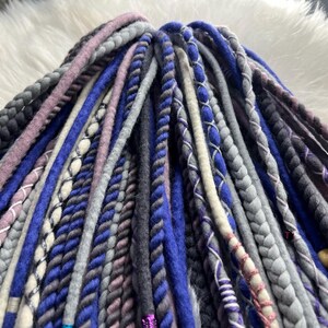 A close-up image of various braided hair accessories in different colors and patterns, including blue, gray, purple, and pink braids.