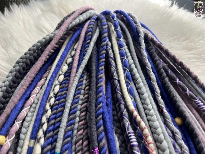 A close-up image of various braided hair accessories in different colors and patterns, including blue, gray, purple, and pink braids.