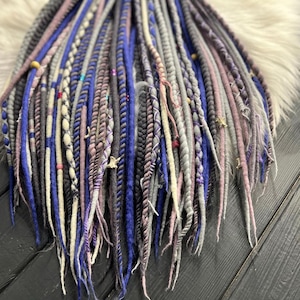 a variety of colorful braided hair accessories, including long braids with different patterns and colors, arranged on a wooden surface.
