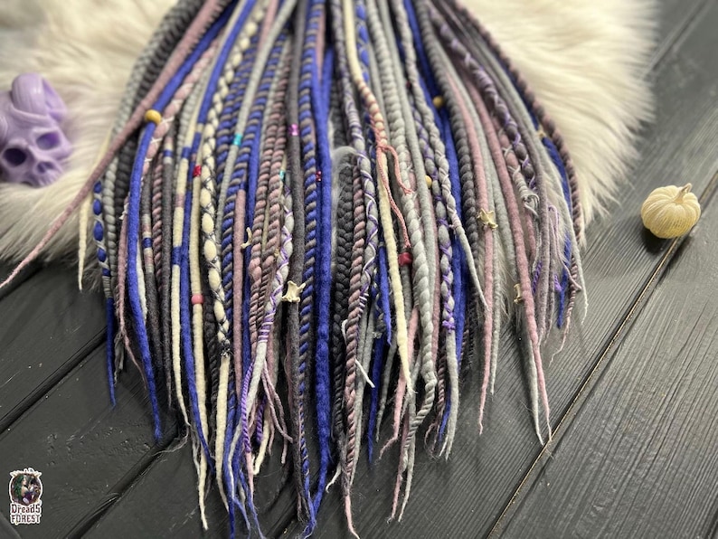 a variety of colorful braided hair accessories, including long braids with different patterns and colors, arranged on a wooden surface.