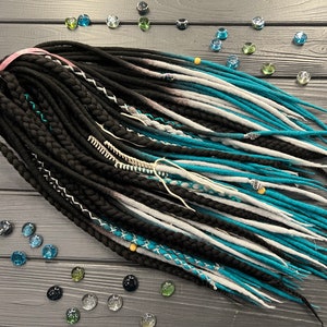 May include: A set of black, white, and turquoise wool dreadlocks. The dreadlocks are tied together with a pink ribbon.
