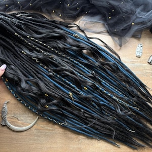 May include: Black and blue dreadlocks with gold detailing. The dreads are displayed on a wooden surface. The Dread5 Forest logo is visible. Decorative items include a silver raven and crescent moon.