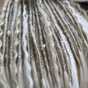 a close-up view of various braided and twisted hair strands in different shades of white and gray.