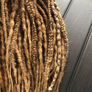 a close-up view of a collection of braided hair strands, with a wooden surface in the background.