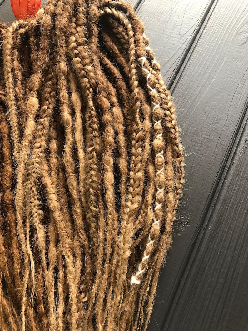 a close-up view of a collection of braided hair strands, with a wooden surface in the background.