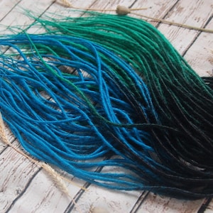 a collection of colorful hair dyes in various shades of blue, green, and black, arranged on a wooden surface.