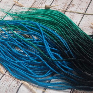 A collection of colorful hair dyes in various shades of blue, green, and black, arranged on a wooden surface.