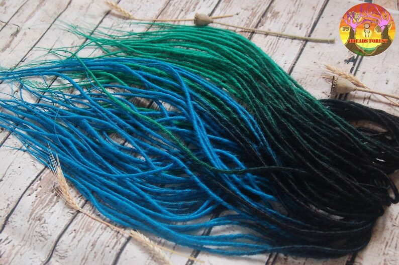 A collection of colorful hair dyes in various shades of blue, green, and black, arranged on a wooden surface.
