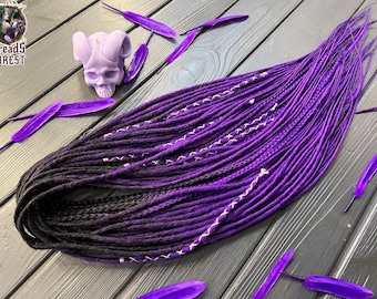 Könnte beinhalten: Ein Satz synthetischer Dreadlocks mit einem Farbverlauf von Schwarz zu Lila. Die Dreadlocks sind mit weißem Garn zusammengebunden und haben einen dezenten Glanz.