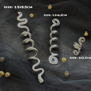May include: Three silver hair clips in different sizes. The largest clip is 1.5x9.5 cm, the middle clip is 1.1x6.2 cm, and the smallest clip is 1x3.3 cm. All three clips are shaped like a spiral.