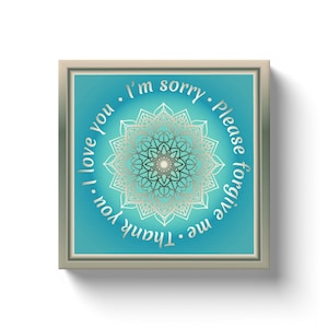 May include: Square framed art print with a teal gradient background and a silver mandala design. The text "I love you, I'm sorry, Please forgive me, Thank you" is written around the mandala.
