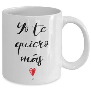 Peut inclure: Mug en c&eacute;ramique blanche avec l'inscription en espagnol "Yo te quiero m&aacute;s" en &eacute;criture noire, et un petit c&oelig;ur rouge. La tasse a une anse incurv&eacute;e et convient aux boissons chaudes ou froides.