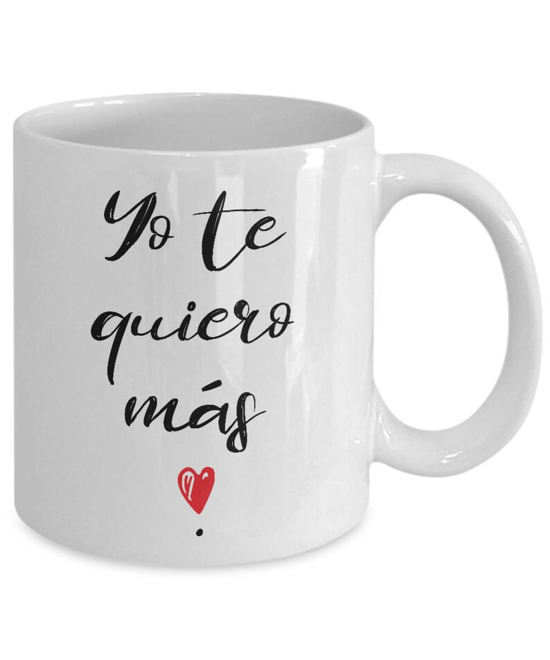 Peut inclure: Mug en c&eacute;ramique blanche avec l'inscription en espagnol "Yo te quiero m&aacute;s" en &eacute;criture noire, et un petit c&oelig;ur rouge. La tasse a une anse incurv&eacute;e et convient aux boissons chaudes ou froides.