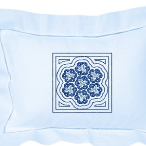 Peut inclure: Un oreiller bleu clair avec un carré brodé décoratif au centre. Le carré présente un motif répétitif de motifs bleus et bleu clair en forme de nœuds. L'oreiller a un bord festonné et une bordure cousue.
