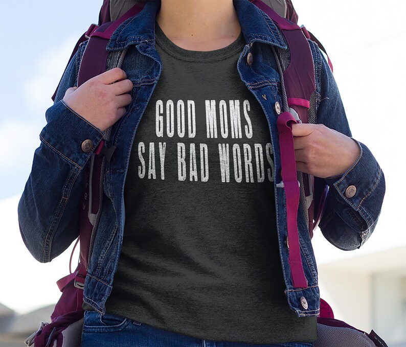 May include: A dark grey t-shirt with the text "GOOD MOMS SAY BAD WORDS" printed in white.
