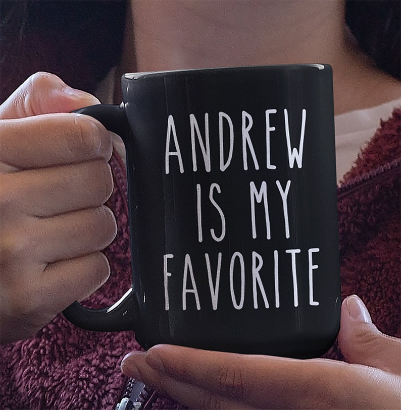 May include: Black ceramic mug with white text that reads "ANDREW IS MY FAVORITE".