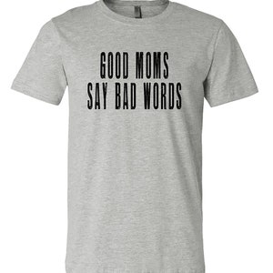 May include: A heather grey t-shirt with the text "GOOD MOMS SAY BAD WORDS" printed in black.