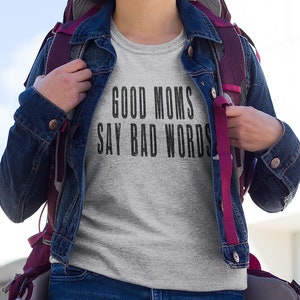 May include: A grey t-shirt with the text "GOOD MOMS SAY BAD WORDS" printed in black.