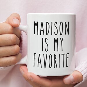 May include: White ceramic mug with black text that reads "MADISON IS MY FAVORITE".