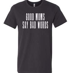 May include: A dark grey t-shirt with the text "GOOD MOMS SAY BAD WORDS" printed in white.