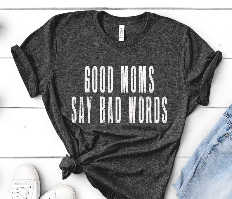 May include: A dark grey t-shirt with the text "GOOD MOMS SAY BAD WORDS" printed in white.