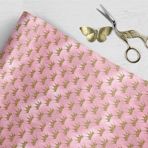 May include: Pink wrapping paper with a repeating pattern of gold glitter crowns.