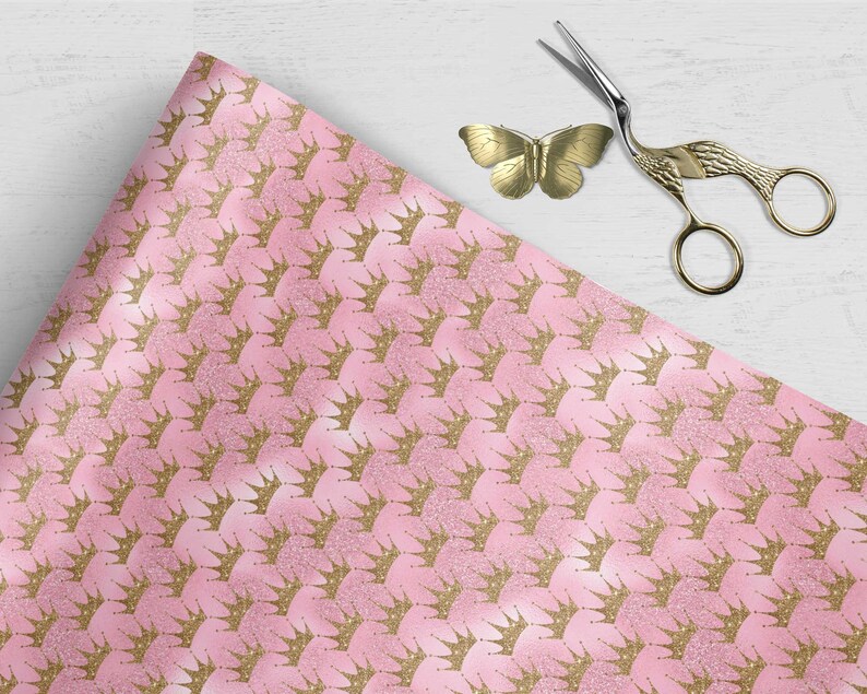 May include: Pink wrapping paper with a repeating pattern of gold glitter crowns.