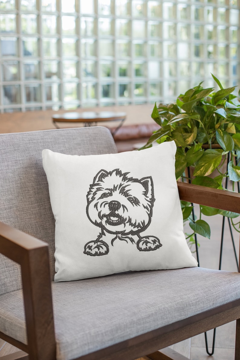 K&ouml;nnte beinhalten: Ein wei&szlig;es Kissen mit einem schwarzen und wei&szlig;en gestickten Bild eines Westie-Hundes, der &uuml;ber die Oberseite des Kissens schaut.