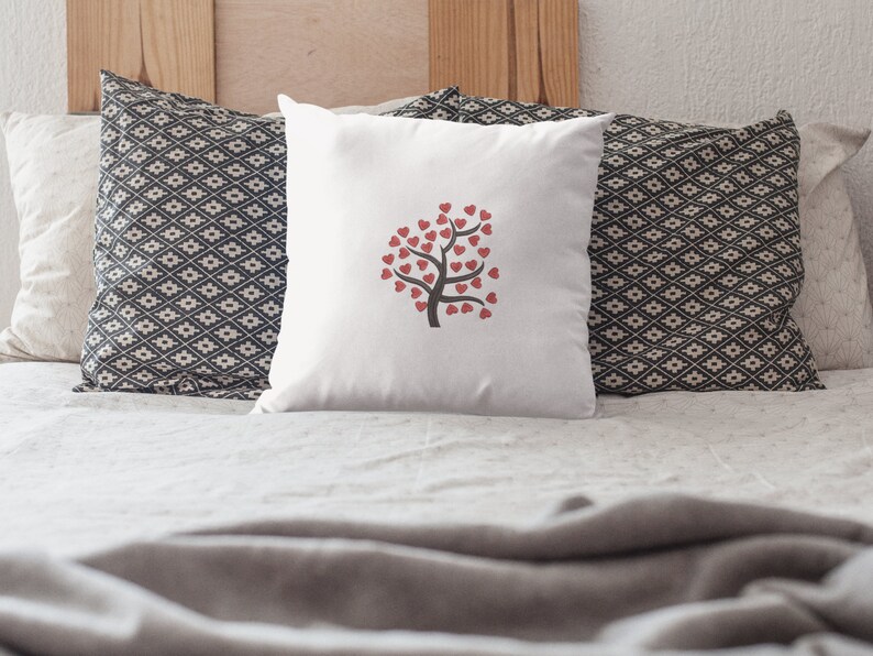 Puede incluir: Almohada blanca con un dise&ntilde;o de &aacute;rbol de corazones rojos. La almohada est&aacute; sobre una cama con una funda n&oacute;rdica blanca y dos almohadas con estampado blanco y negro.
