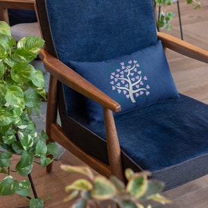 Puede incluir: Un sill&oacute;n azul con marco de madera y un coj&iacute;n con un dise&ntilde;o de &aacute;rbol de corazones rosas.