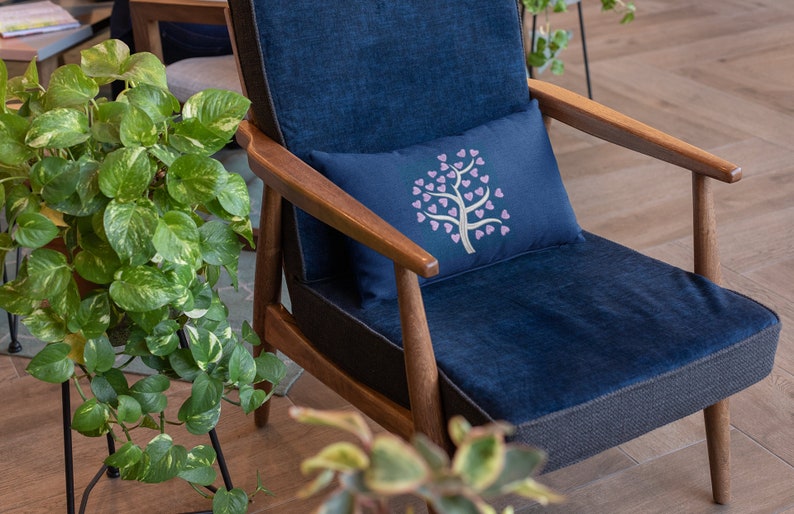 Puede incluir: Un sill&oacute;n azul con marco de madera y un coj&iacute;n con un dise&ntilde;o de &aacute;rbol de corazones rosas.