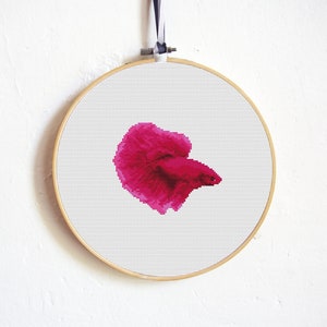 May include: A pink betta fish cross-stitch pattern in a wooden embroidery hoop.