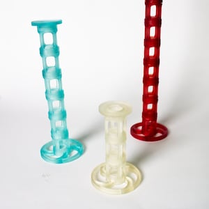 Peut inclure: Trois tours en plastique, une bleue, une rouge et une blanche. Chaque tour a un centre creux et plusieurs anneaux.
