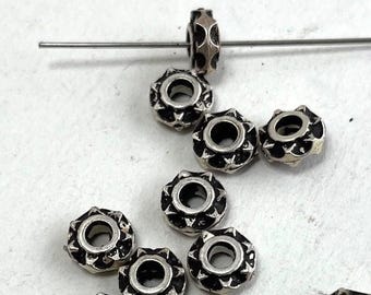 May include: A collection of silver-toned metal beads with a starburst design. The beads have a small hole in the centre for stringing.