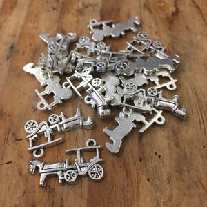May include: A pile of silver-toned metal charms in the shape of horse-drawn carriages. The charms are detailed and have a vintage look.