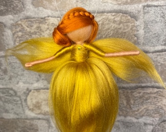 May include: A handmade felt fairy doll with long, flowing golden hair and a golden dress. The doll has a braided orange hairpiece and a beaded face.