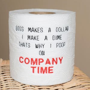 May include: A white toilet paper roll with the text "Boss makes a dollar, I make a dime, that's why I poop on company time" printed in black. The words "company time" are printed in red.