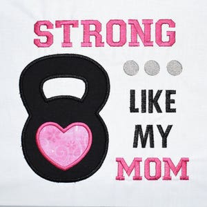 May include: A black kettlebell with a pink heart design and the text "STRONG LIKE MY MOM" in pink and black lettering.