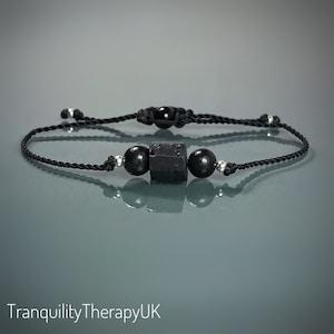 May include: Black beaded bracelet with a black obsidian stone charm. The bracelet is made with black cord and silver beads.