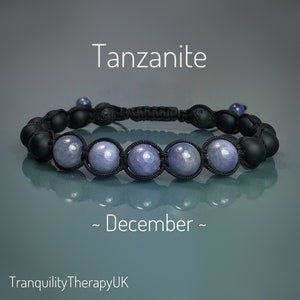 May include: A Tanzanite bracelet with black beads and a woven cord. The bracelet features five light purple Tanzanite stones, with the word "Tanzanite" and "December" in white text. The shop name "TranquilityTherapyUK" is also visible.