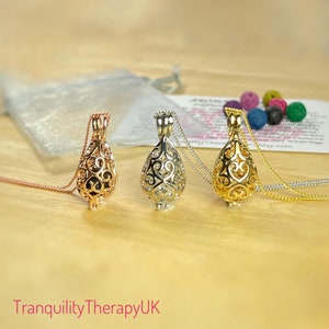 May include: Three silver, gold, and rose gold aromatherapy necklaces with a teardrop-shaped cage pendant. The pendants have a delicate filigree design.