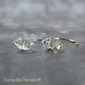 May include: A pair of gold hoop earrings with clear crystal accents. The crystals are faceted and have a geometric shape.