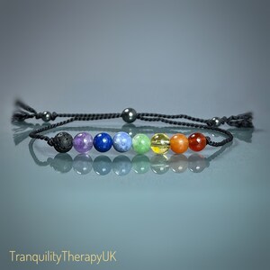 May include: A black cord bracelet with seven round beads in rainbow colours. The beads are black, purple, blue, light blue, green, yellow, and orange.